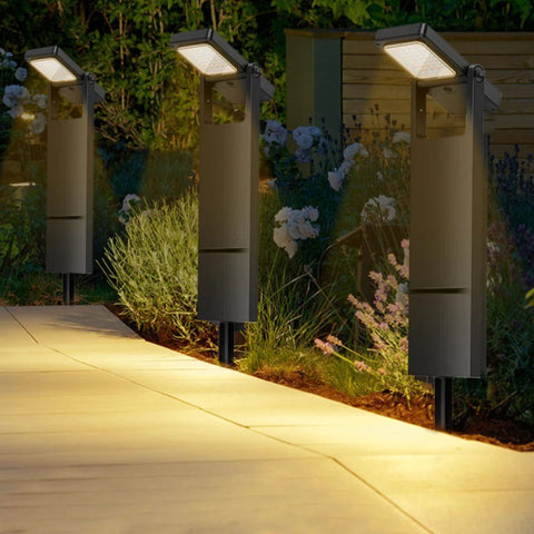 Modern adjustable solar pathway lights illuminating a garden walkway at night, featuring a sleek black design with rotatable LED heads and ground stakes for stability.