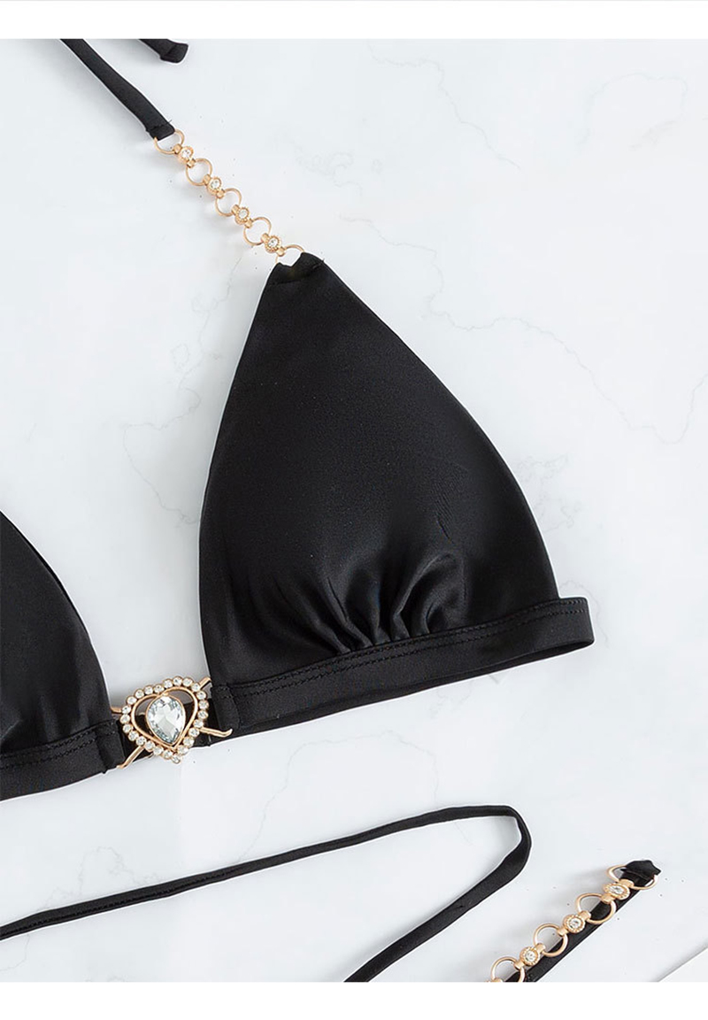 A close-up view of a black triangle bikini with chain straps and a heart-shaped embellishment, focusing on the details of the fabric and design.