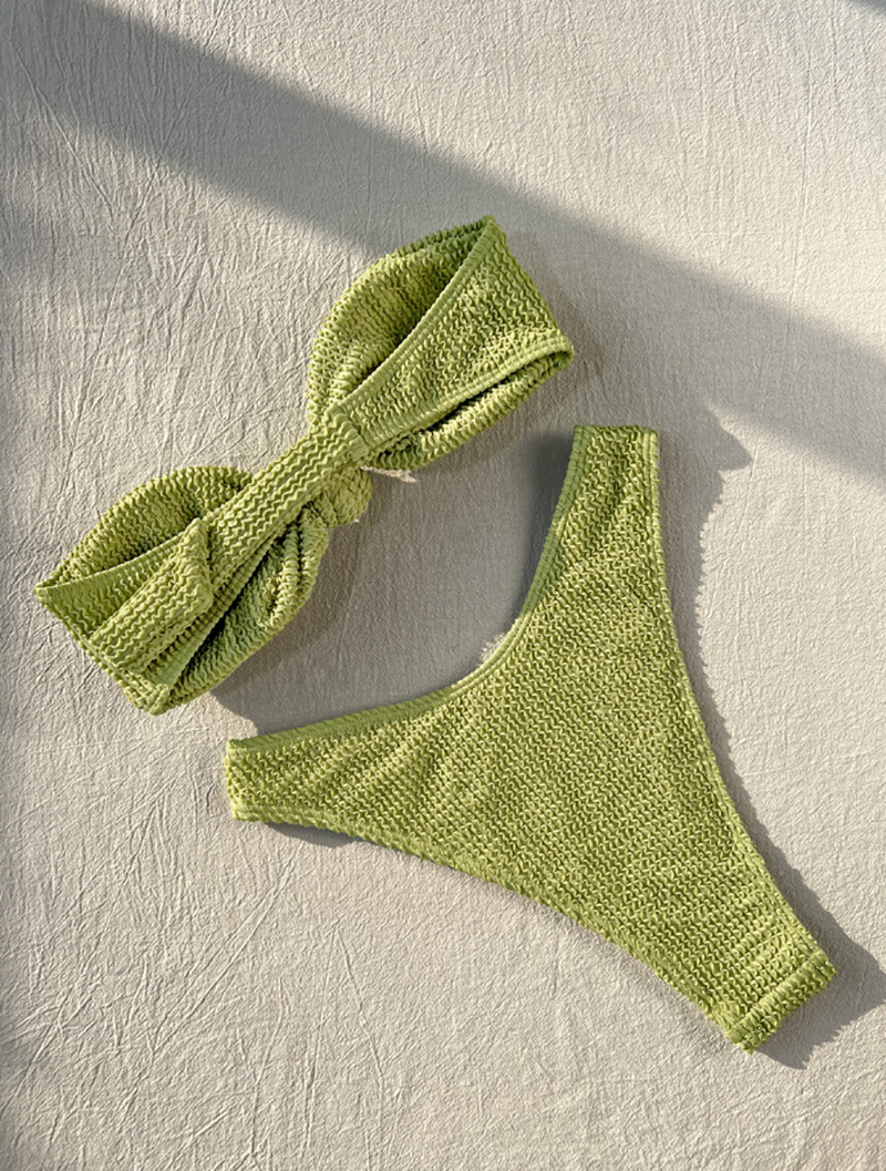A green knitted bandeau bikini top with padding, highlighting its supportive features.