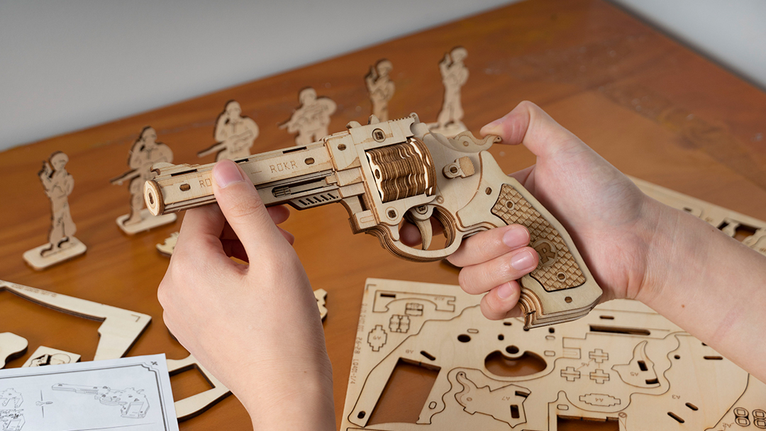 A man assembling a wooden revolver.