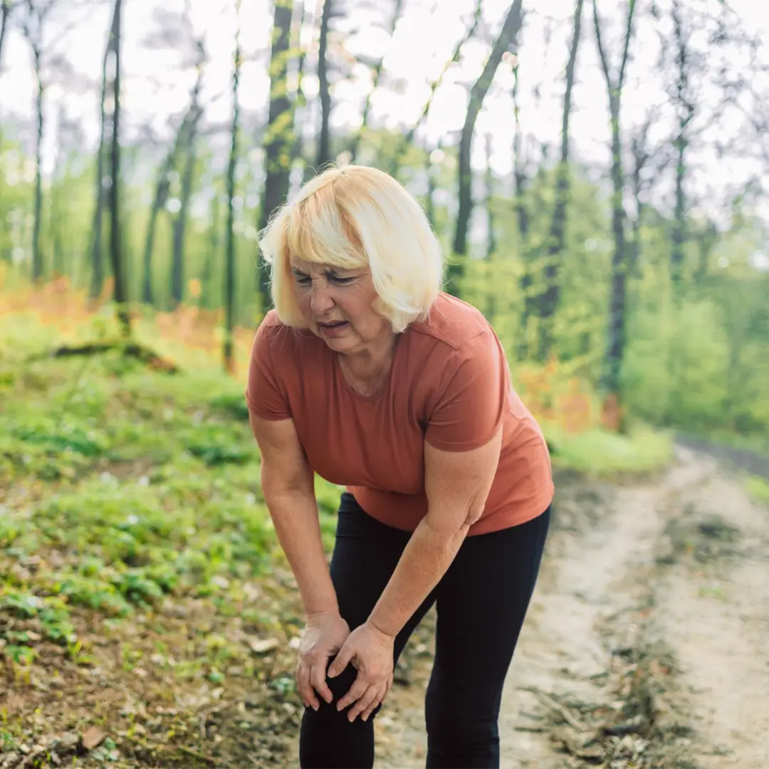 Elderly woman catching her breath in a forest.